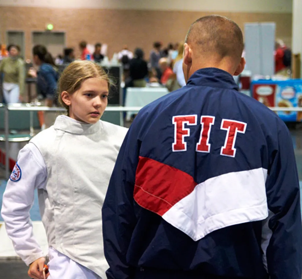 A Fencing Institute of Texas coach speaking with a young competitor