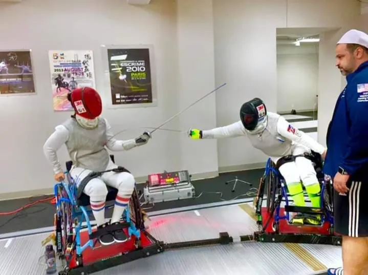 Wheelchair fencers competing with a coach nearby