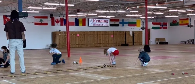 Young fencers training together on the Fencing Institute of Texas floor
